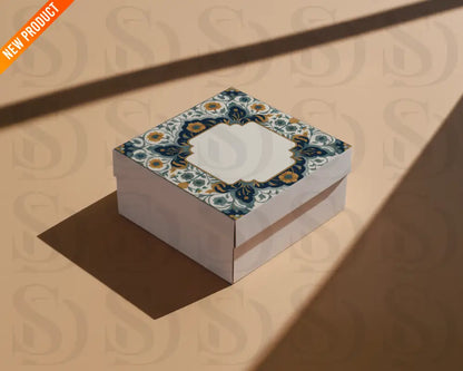 Square gift box with a Mughal-inspired midnight blue and gold floral frame design printed on the lid, photographed on a warm beige background.