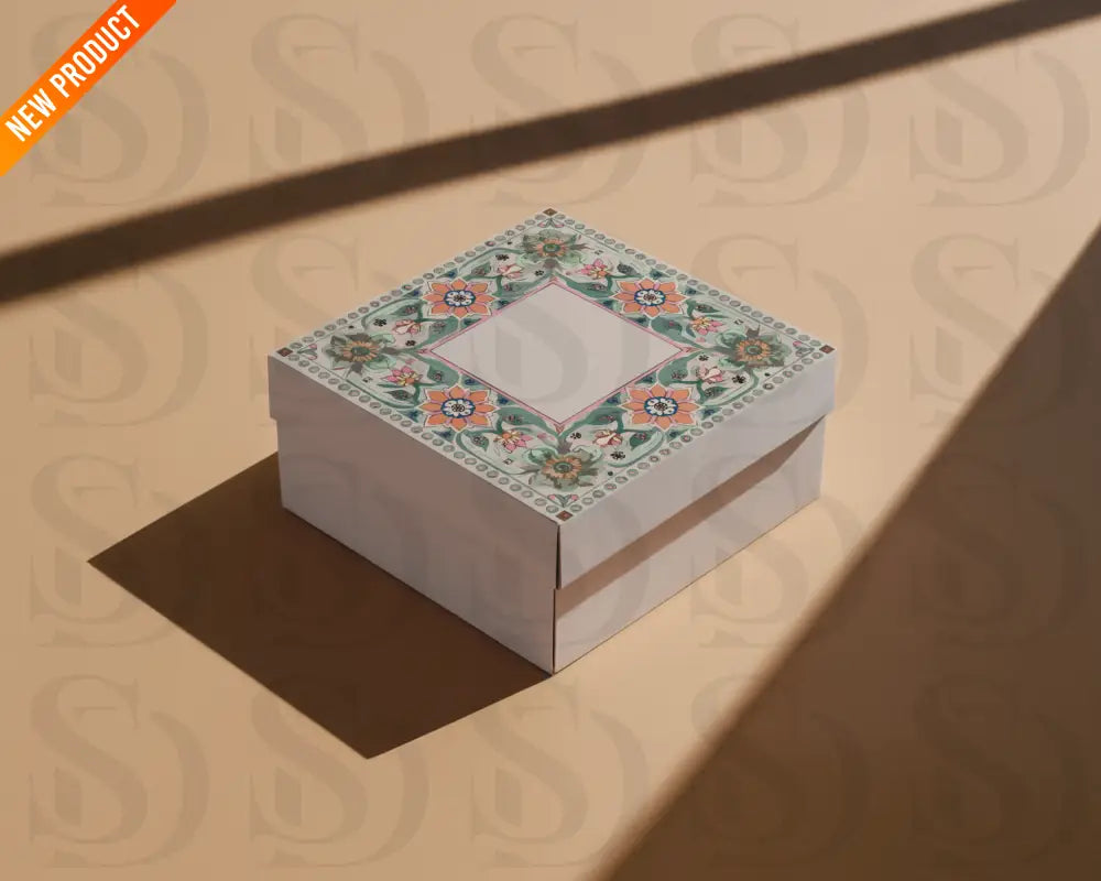 Square gift box with Mughal-inspired floral wedding card artwork printed on the lid, photographed on a warm beige background with shadows.